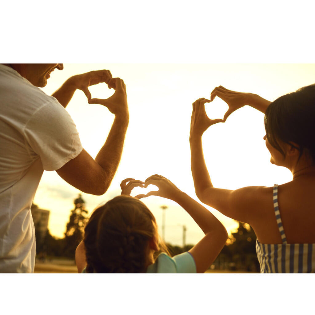 Parents and child holding up hands in shape of heart