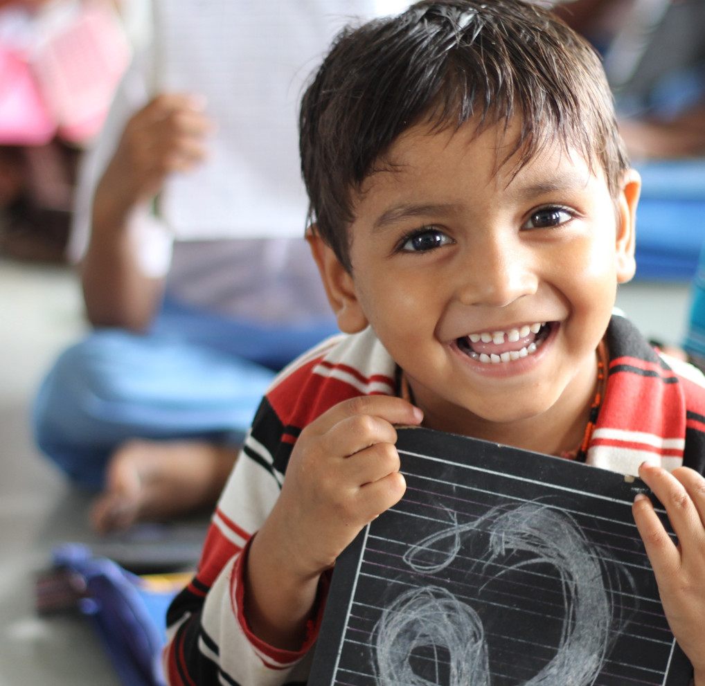 Happy child holding up a chalkboard drawing