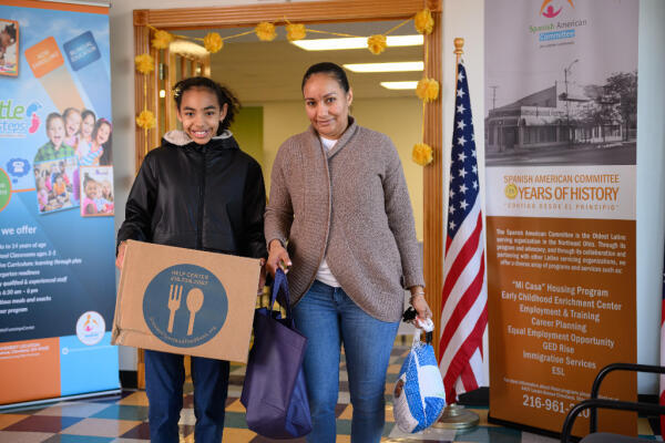 A Hispanic mother and her daughter receive a food box from the Greater Cleveland Food Bank