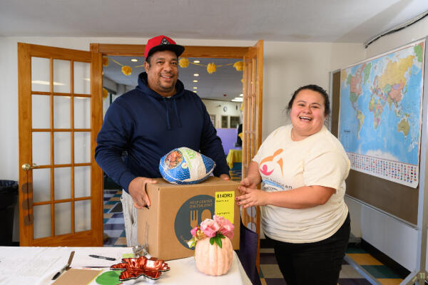 Our Social Services Coordinator gives a Thanksgiving turkey and food box to a Latino man
