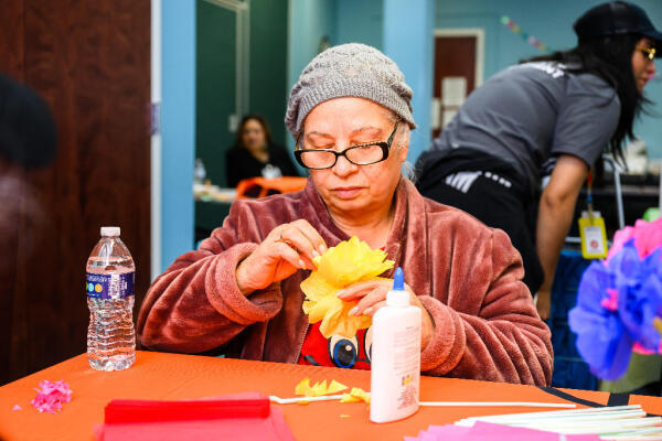 A Hispanic woman enjoys making crafts at our senior social program