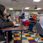 Staff member speaking with a participant at a table with informational materials during a job-fair event