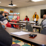 Staff member speaking with a participant at a table with informational materials during a job-fair event