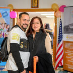 Two program participants standing together in front of workforce development and housing banners, smiling
